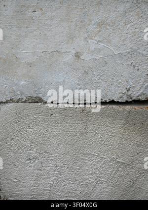 Vertical close up of two stacked concrete barrier blocks with a visible gap between them, rough uneven cement surfaces Stock Photo