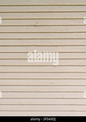 Vertical close up of weathered cream painted narrow bevel lap siding with flat overlapping boards, rough uneven wood surface Stock Photo