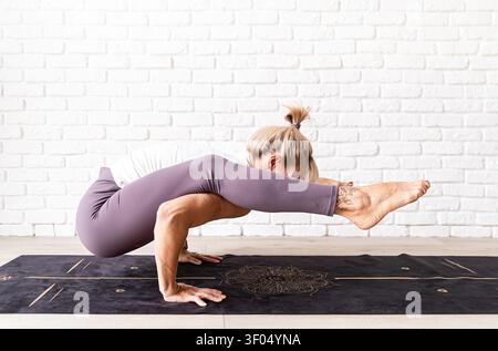 Active lifestyle. Young attractive woman wearing sportswear practicing yoga at home. Indoor full length, white brick wall background Stock Photo