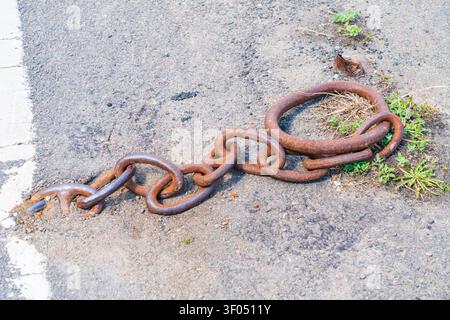 Close up of rusted quayside mooring ring and chain assembly links on the concrete floor of a wharf or dock Stock Photo