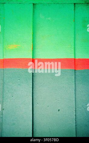Storefront wall in the Dominican Republic painted in two shades of green, divided by a bold red stripe, captured on analog film. Stock Photo