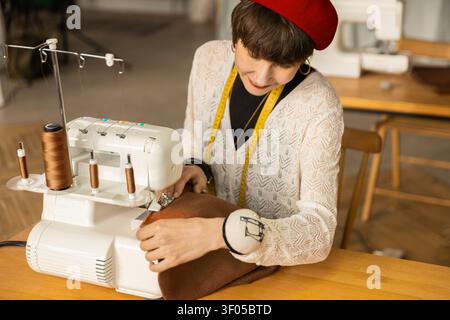 High angle view of focused female fashion creator using white serger Stock Photo