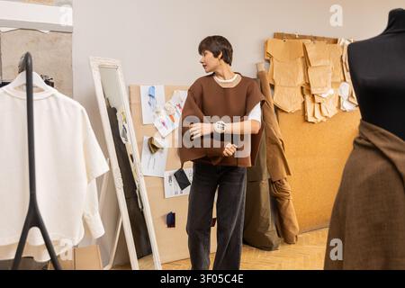 Fashion designer looking in mirror adjusting top sleeve Stock Photo