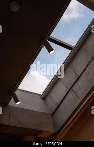 Blue sky and fluffy clouds through an industrial concrete ceiling skylight Stock Photo