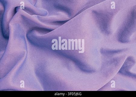 Horizontal macro top view of wrinkled mauve polyester fabric texture showing fine diagonal ribbed lines on smooth synthetic athletic apparel material Stock Photo