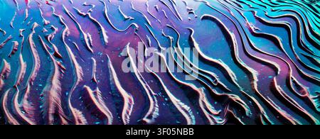 Abstract iridescent ripple textures of colorful reflections in wet sand. Stock Photo