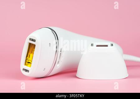 Close up of white IPL photoepilator and precision attachment on pink background. Modern beauty device for removing unwanted hair, technology for home Stock Photo