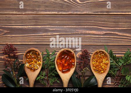 Spoons with different pills and plants on wooden background Stock Photo