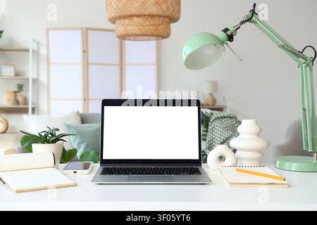 Blank laptop with plant and lamp on programmers desk in living room Stock Photo