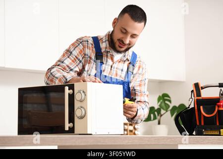 Technician repairing microwave oven in kitchen Stock Photo