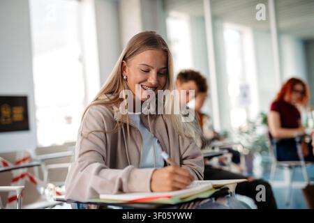 Female student writing notes during university lecture. Stock Photo
