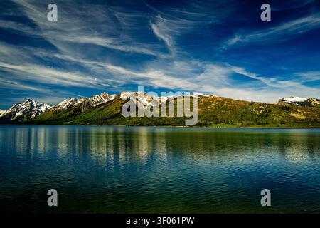 Dramatic wispy cirrus clouds sweep across a deep blue sky above the Grand Tetons. Stock Photo