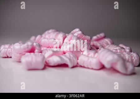 Pink packing foam pieces used for shipping protection, shown in a studio closeup to represent packaging, cushioning, and transport safety. Stock Photo