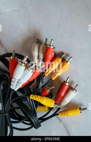 Several audio and video cables are placed on a flat surface. They have various colored connectors including red, yellow, and white. The cables are tan Stock Photo