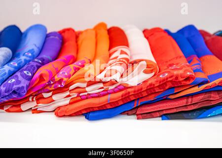Large row of colorful silk scarves with vibrant abstract patterns arranged on white background Stock Photo