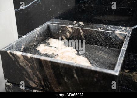 Luxury bathroom sink made of black marble with elegant veining in commercial restroom. Premium hygiene and sophisticated interior design. Stock Photo