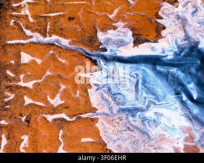 Full color fine art abstract of magical water swirling into warm sand, creating marbled foam, flowing lines, and dreamy texture like an aerial shoreli Stock Photo