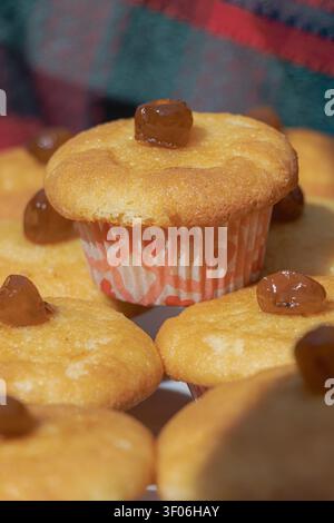 Close-up of homemade vanilla muffins topped with raisins, presented on a bakery display in warm natural light, highlighting soft texture, artisan baki Stock Photo
