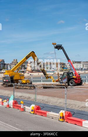 Weymouth Dorset England UK. 02.07.2026. two telescopic handlers and a boom lift are actively engaged in construction work along a coastal promenade, w Stock Photo