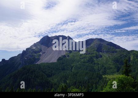 Mountain Peak Above Forested Valley Under Dramatic Cloudy Sky Stock Photo