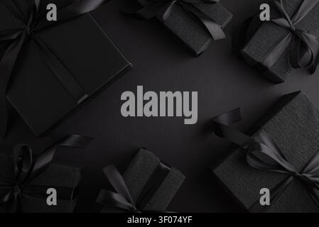Black gift boxes with a satin ribbon on a matching dark background, symbolizing luxury, elegance, and exclusivity for promotions, celebrations, and sp Stock Photo