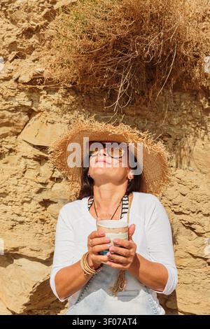 Close up of woman in straw hat enjoying sunlight and coffee Stock Photo