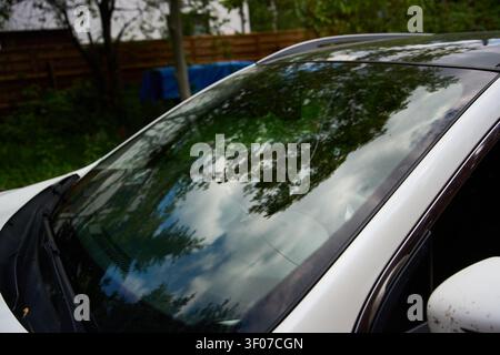Broken windshield. Damaged auto glass shows deep crack on surface. Vehicle awaits windshield replacement or resin repair service. Stock Photo