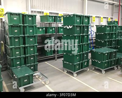 Stacks of green plastic crates arranged on shelves in an industrial warehouse. Stock Photo