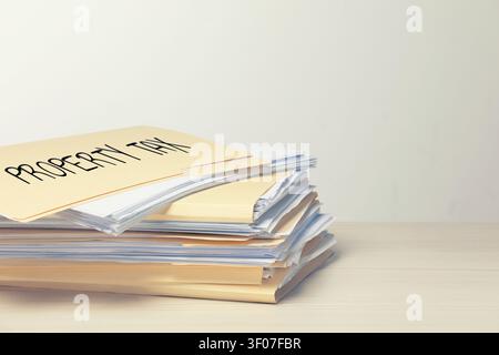 Property tax. Stacked folders with documents on wooden table. Space for text Stock Photo