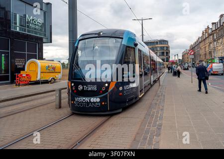 An Edinburgh Trams vehicle carrying the distinctive Vision Scotland advertising livery passes outside Haymarket railway station in Edinburgh, Scotland Stock Photo