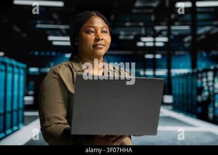 Software engineer works with notebook computer in sustainable server facility, rolling out green technologies. Stock Photo
