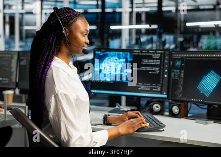 Administrator wears a headset in a server hub, using artificial intelligence troubleshooting to assist users. Stock Photo