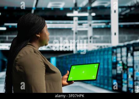 Data center engineer works with a chroma key tablet, using an editable screen to monitor anomaly detection. Stock Photo