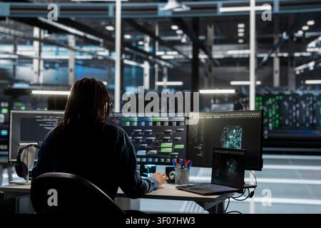 Data center engineer uses a digital device in a data center to support automation monitoring and reliable server workflows. Stock Photo