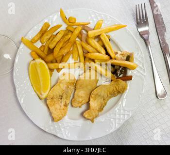 Battered fish with lemon and potatoes Stock Photo