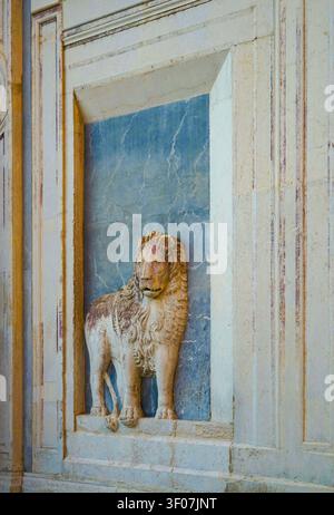 Weathered stone lion statue in faux marble niche, Scuola Grande di San Marco marble facade with false perspective, Venice Italy Stock Photo