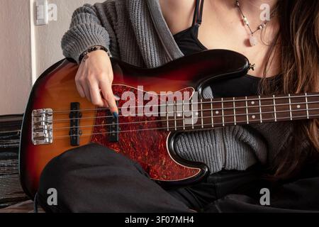 Close-up of a young female musician playing an electric bass guitar Stock Photo