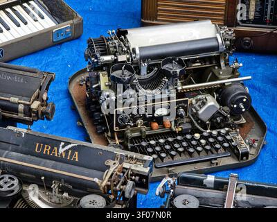 XALO, SPAIN - JUNE 20, 2026.At an antique swap meet, typewriters are placed on a blue sheet. A detailed close up shows a vintage Urania model and othe Stock Photo