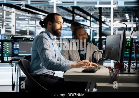 Team of programmers working with workstation in server environment, analyzing data. Stock Photo