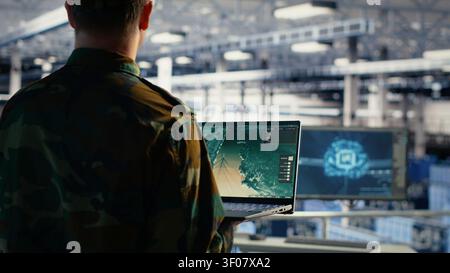 Military engineer in a military data center monitors satellite coordinates with radar software, scanning aerial activity for defense operations. Stock Photo