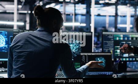 Server room system administrators operate computer to monitor neural network working with AI LLM. Stock Photo
