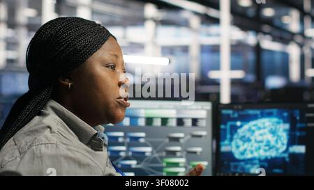 Server facility engineering team rolling out AI solutions optimizing equipment. Server facility teamworking colleagues working together, applying AI to minimize systems downtime. Stock Photo