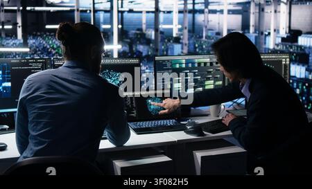 Server room system administrators operate computer to monitor neural network working with AI LLM. Stock Photo