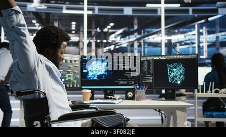 Technical specialist working with wheelchair in data infrastructure center working with AI visual programming system to minimize system downtime with disability working with visual programming. Stock Photo