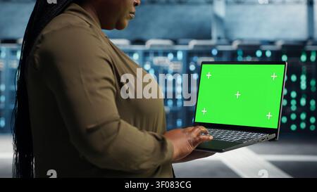 Programmer uses an isolated screen laptop in a server room for editable AI infrastructure review. Stock Photo
