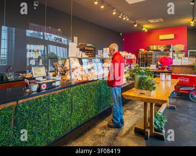 Washington state, United States, JUN 20, 2026 - An elderly man in a red jacket stands at the counter of a bakery looking at a display case filled with Stock Photo