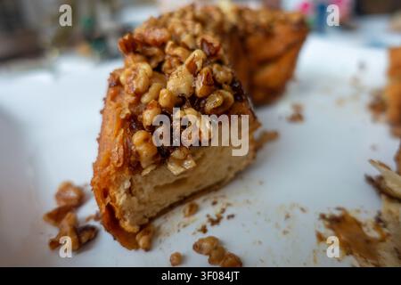A piece of sticky bun bundt cake topped with chopped walnuts on a white plate. Stock Photo