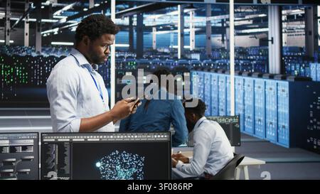 High tech server room technical specialist working with digital tablet to interpret AI generated data analytics graphs with working with AI displaying system operational performance predictive. Stock Photo