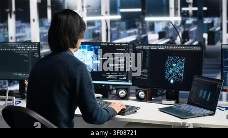 System administrator uses laptop-based deep learning tools in a server room to improve AI operations and system efficiency. Stock Photo