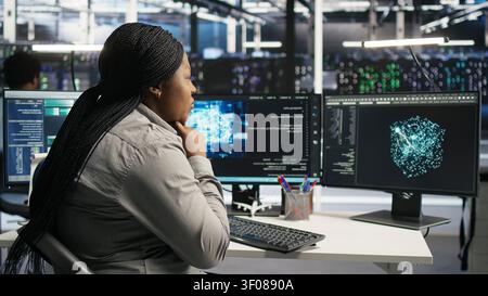 Server facility technical specialist applying AI ML models to set up hardware. African American woman works on AI programming tools in data center, optimizing system. Stock Photo
